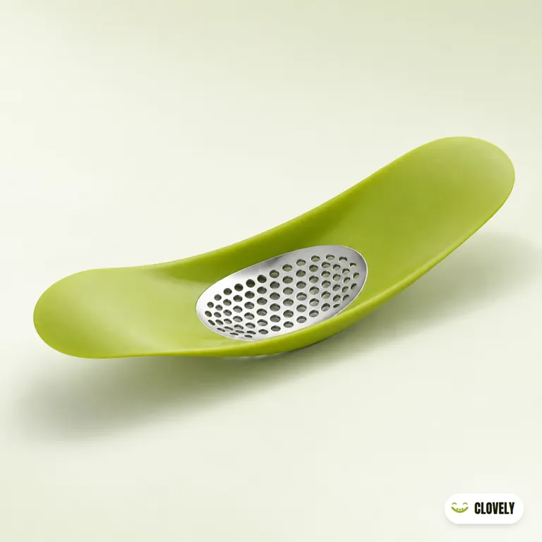 A lime-green curved garlic crusher with an oval perforated plate in its bowl-shaped top, on a pale sage surface.